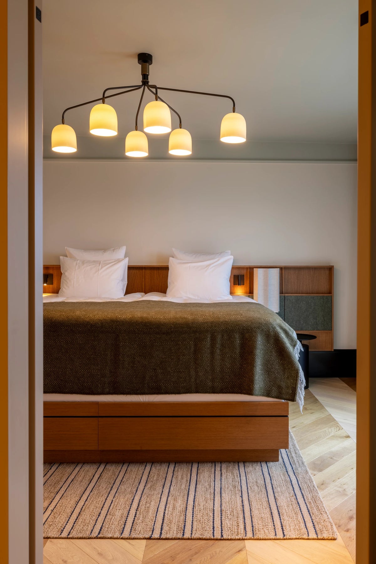 CORI Hornbæk Sky Suite: portrait view of the bed and timber base through the doorway, photographed by Anthony Bogdan.