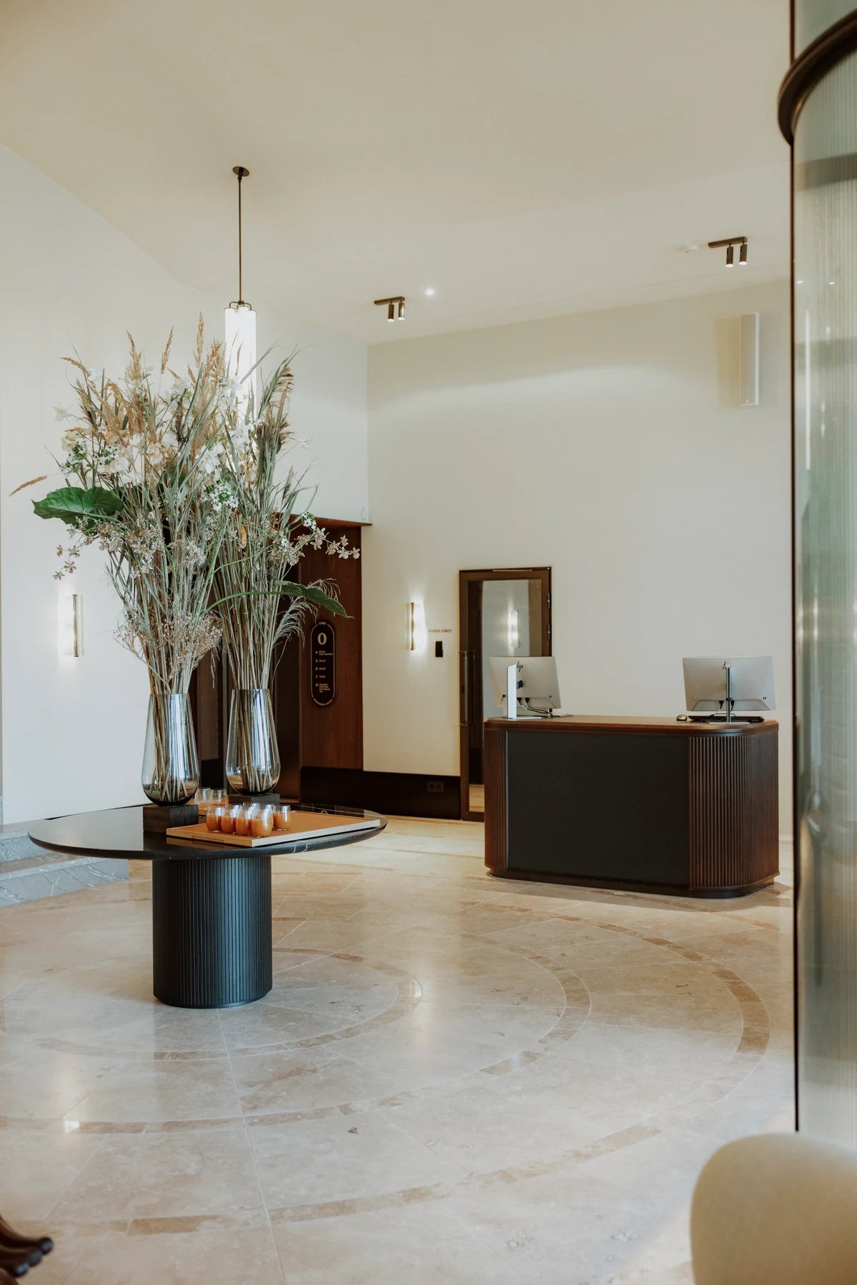 A tall floral arrangement in the bright lobby beside a timber service cabinet at CORI Hornbæk.