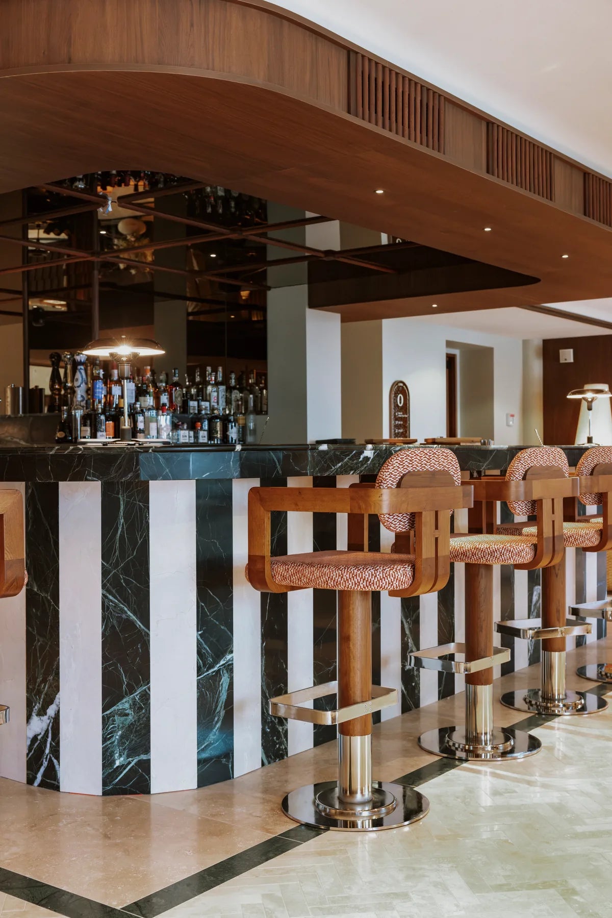 Cane-backed stools beside a marble bar under a curved timber ceiling at CORI Hornbæk.