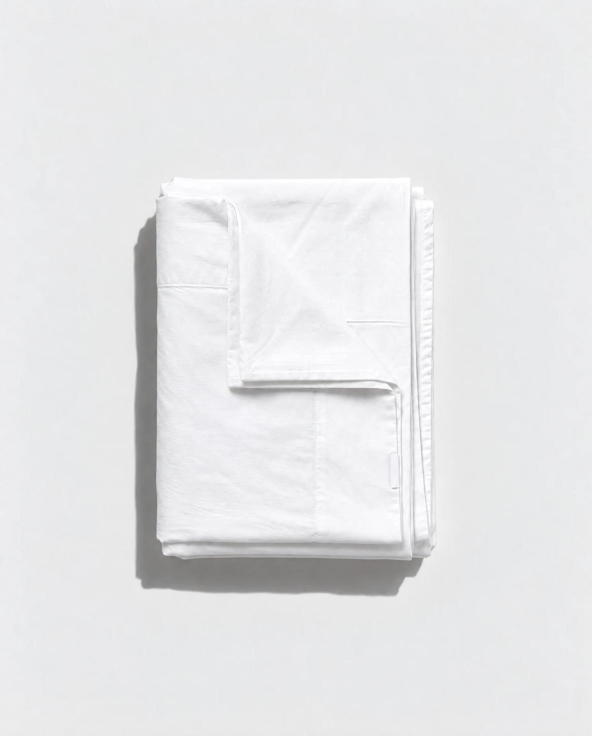 Folded white Geismars duvet cover with visible stitched edges on a pale grey background