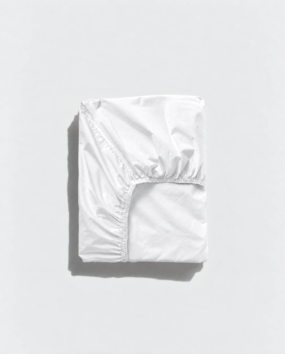 White Geismars fitted sheet folded to show its elasticated edge on a pale grey background