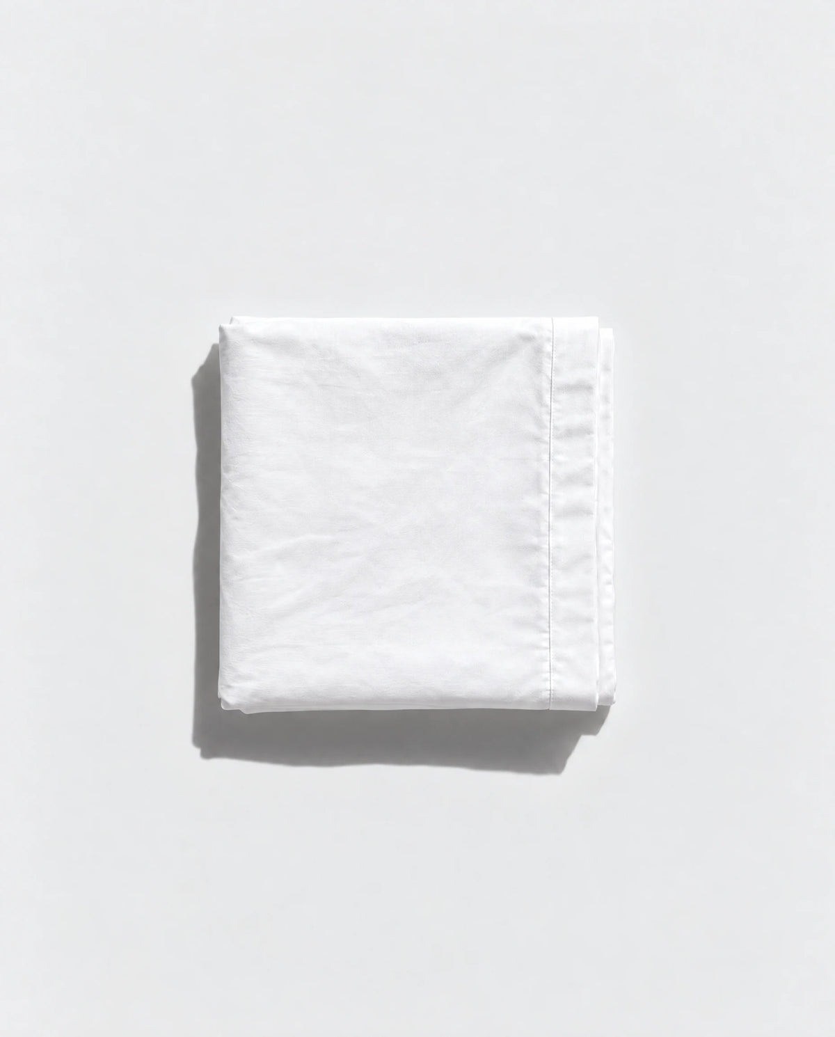 Folded white Geismars pillowcase on a pale grey background